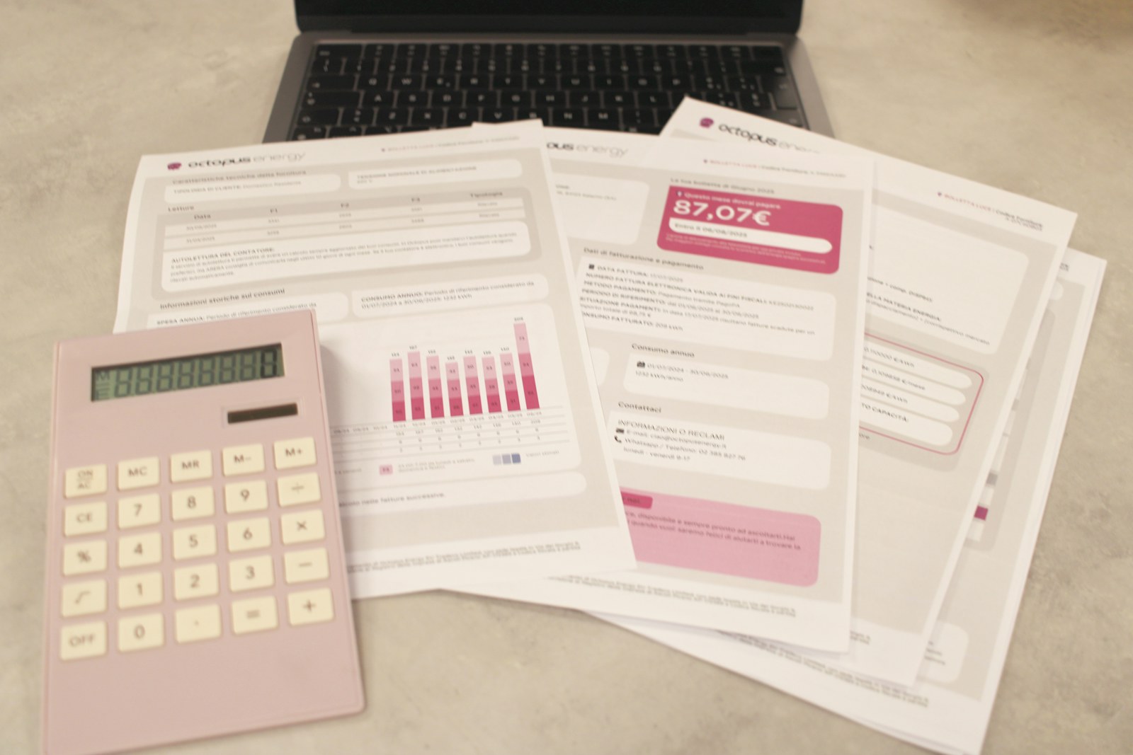 Bills and a calculator beside a laptop